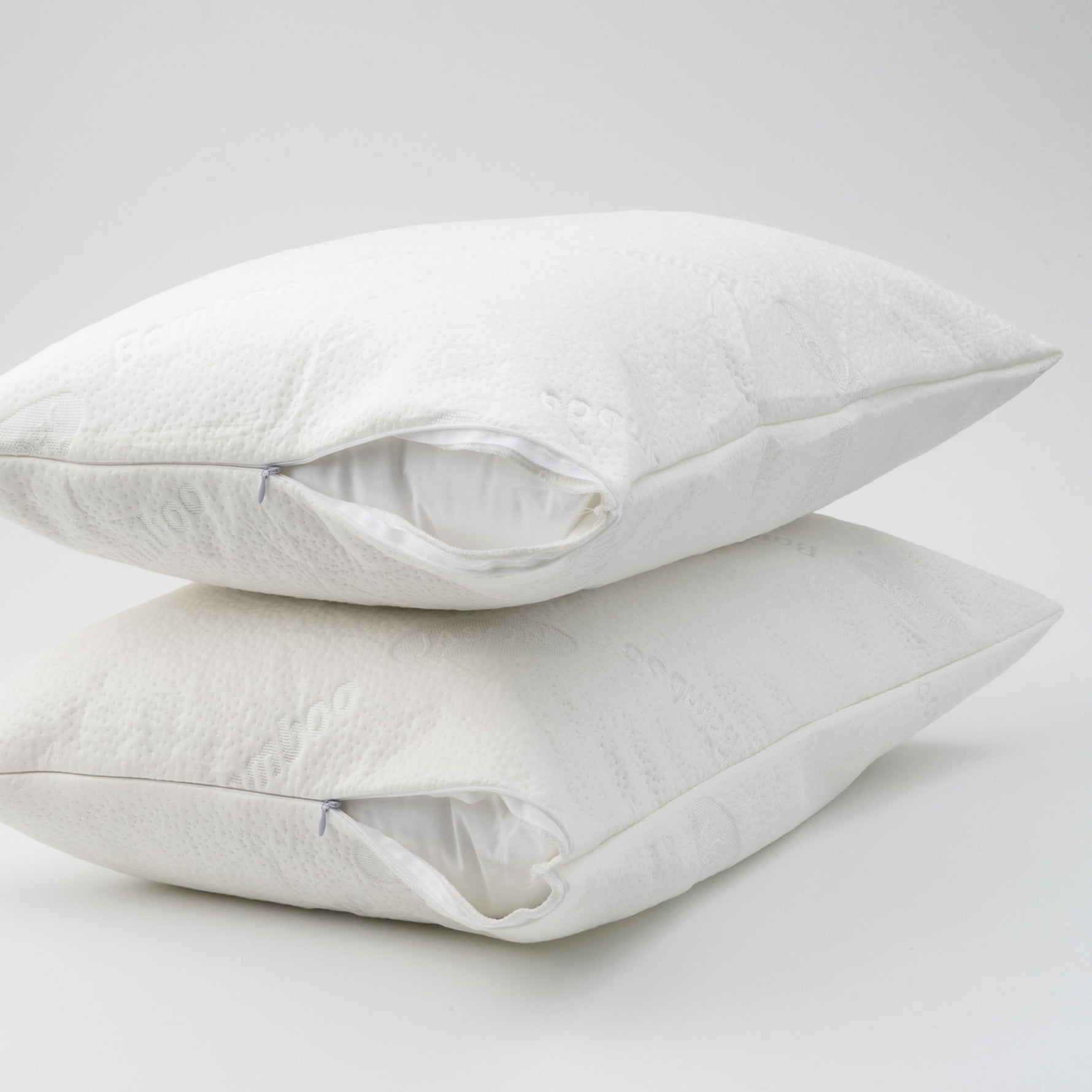Two white waterproof bamboo pillow protectors fitted over pillows with partially opened zip closures, stacked on a white background.