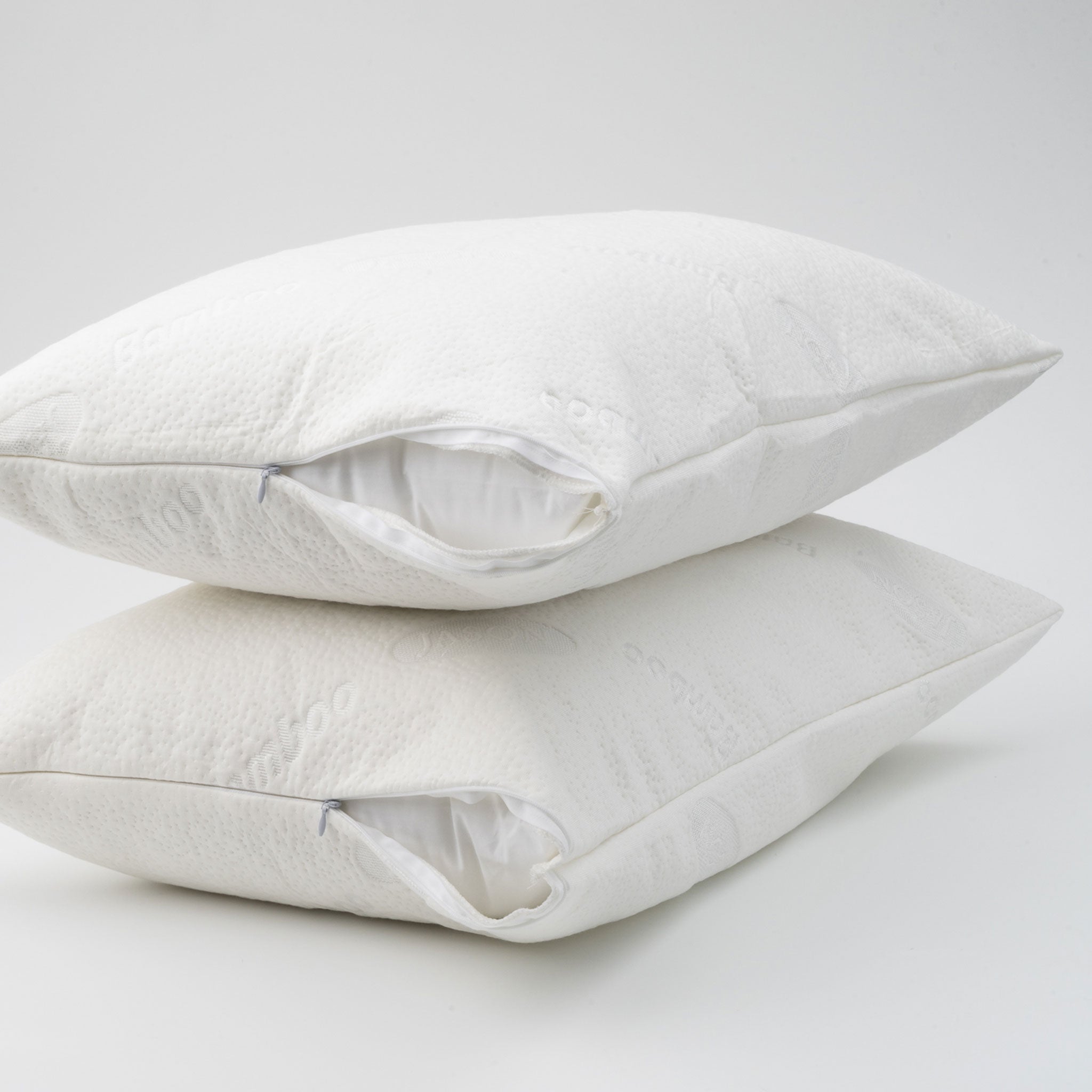 Two white waterproof bamboo pillow protectors fitted over pillows with partially opened zip closures, stacked on a white background.