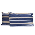 Pair of Brighton Stripe pillowcases featuring horizontal white and beige printed stripes on a midnight blue geometric diamond print background with tailored edges, fitted over pillows on a white background.