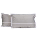 Pair of hazel beige and white Calista pillowcases with white horizontal dashed stripes and white tailored edges, fitted over pillows on a white background.