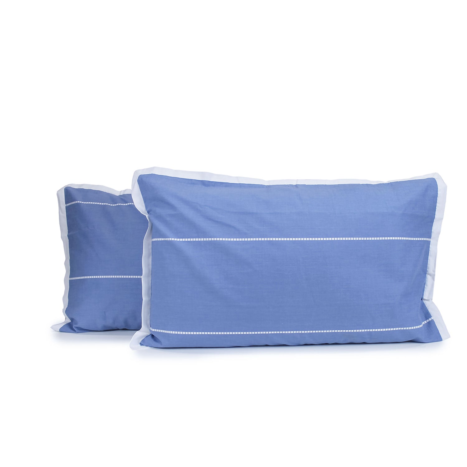 Pair of indigo blue and white Calista pillowcases with white horizontal dashed stripes and white tailored edges, fitted over pillows on a white background.