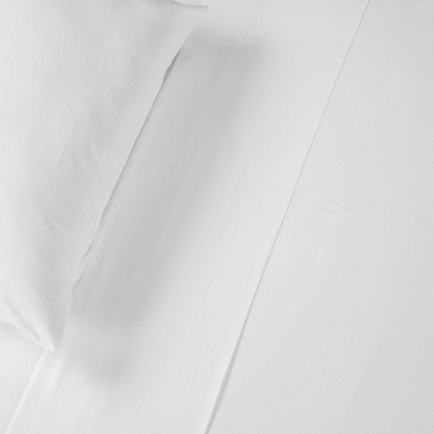 White Cotton Deluxe cotton percale flat sheet with cuff detail and matching pillowcase on a bed.