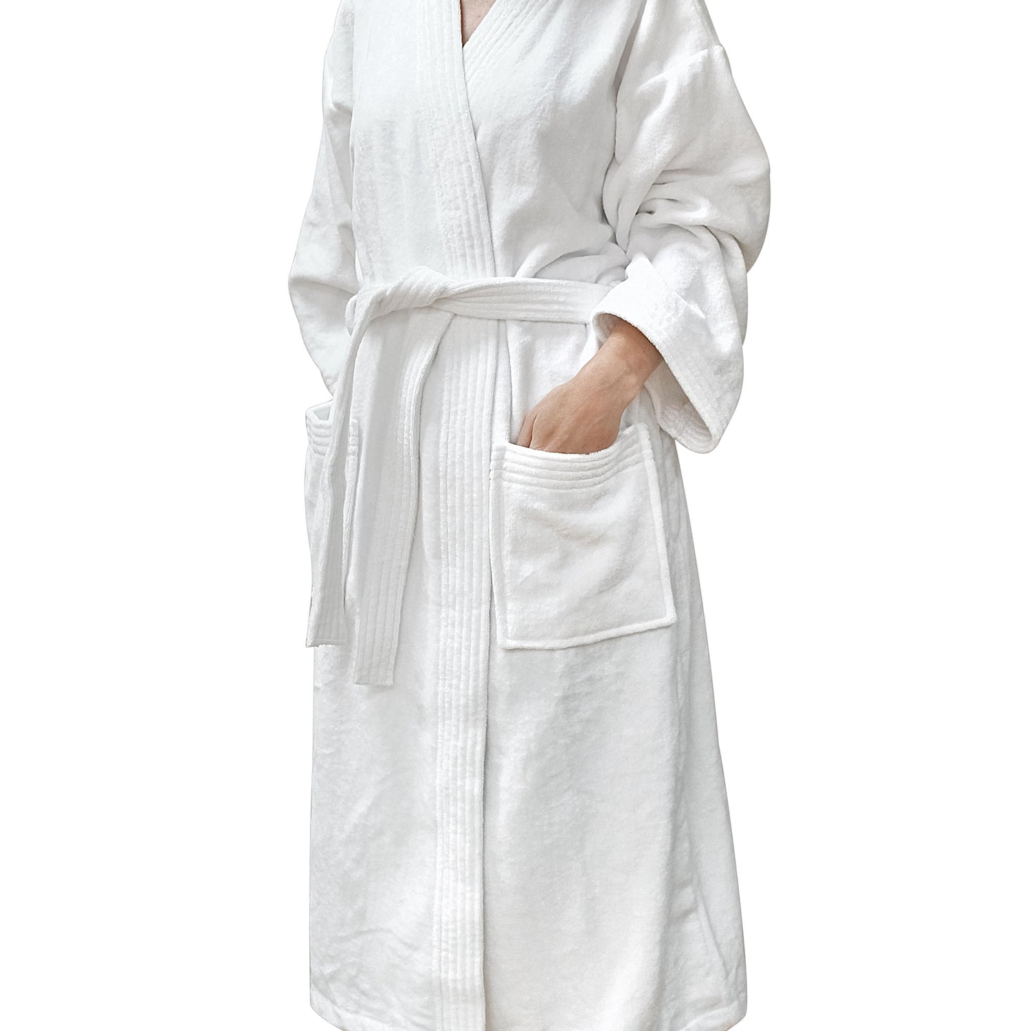 White cotton velour kimono-style bathrobe with a belt tie and patch pockets, modelled with one hand in a pocket against a white background.
