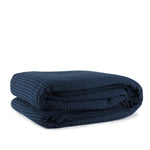 A folded navy blue waffle blanket on a white background.