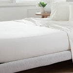 White Crisp poly-cotton percale fitted sheet on a bed with a matching flat sheet, pillow in a matching pillowcase, and a bedside plant near a window.