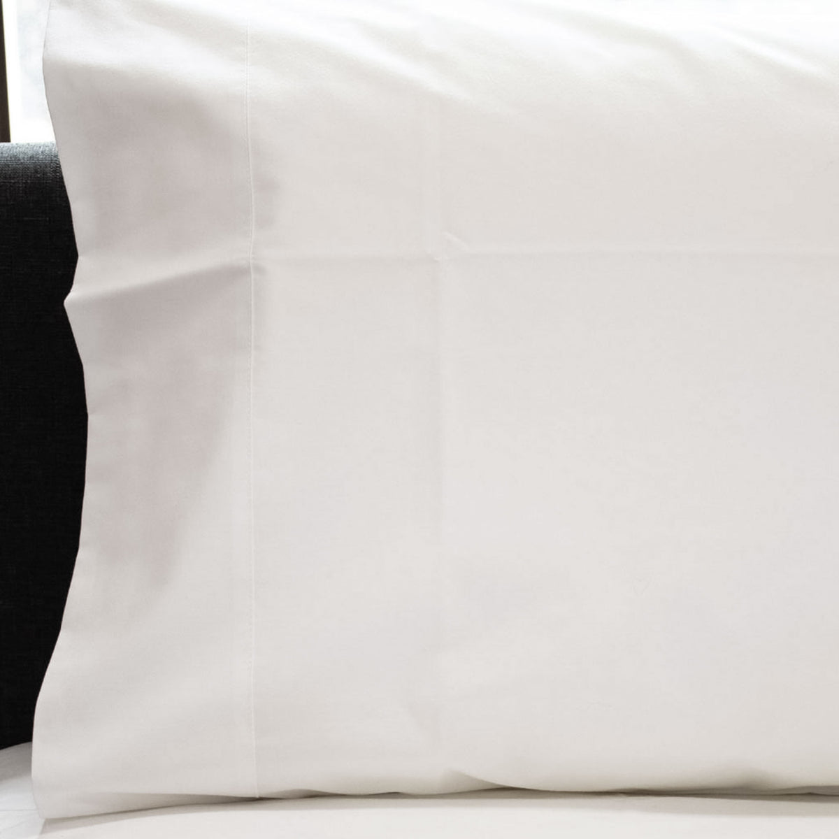 Close-up of a white Crisp poly-cotton percale pillowcase with cuff detail fitted over a pillow.