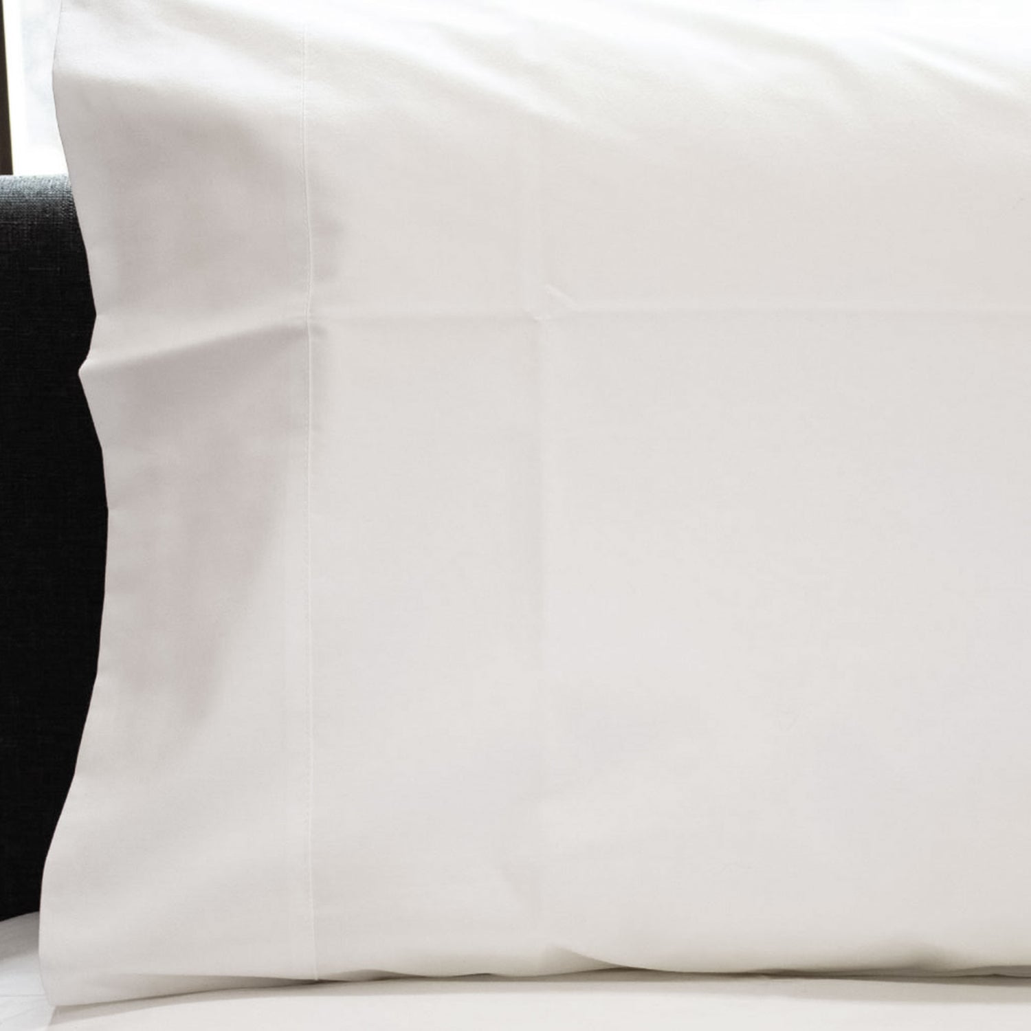 Close-up of a white Crisp poly-cotton percale pillowcase with cuff detail fitted over a pillow.