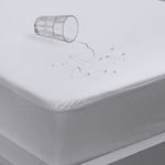 Close-up of a white Eva Clean waterproof mattress protector with water droplets beading on the surface and an overturned glass, fitted over a mattress.