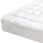 Close-up of a white J-Dream gusseted mattress topper with a square-quilted centre panel, smooth border, gusseted sidewall and fitted skirt over a mattress corner.