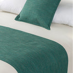 Teal green linen-look bed runner and matching cushion displayed on a bed with white bedding.