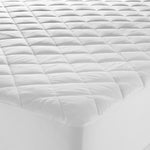 Close-up of a white Microloft mattress protector with a cotton japara cover, diamond-quilted surface and fitted skirt over a mattress corner.