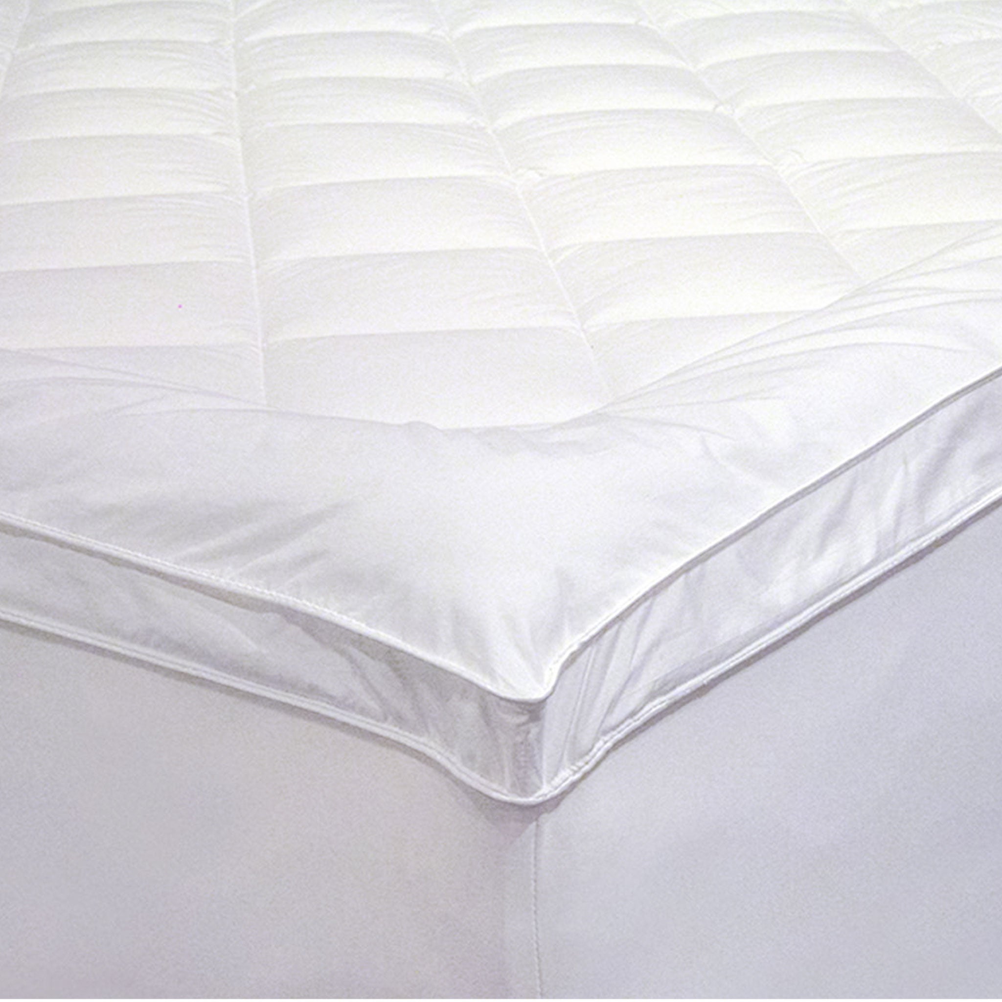 Close-up of a white Microloft gusseted mattress topper with a diamond-quilted centre panel, smooth border, gusseted sidewall and fitted skirt over a mattress corner.