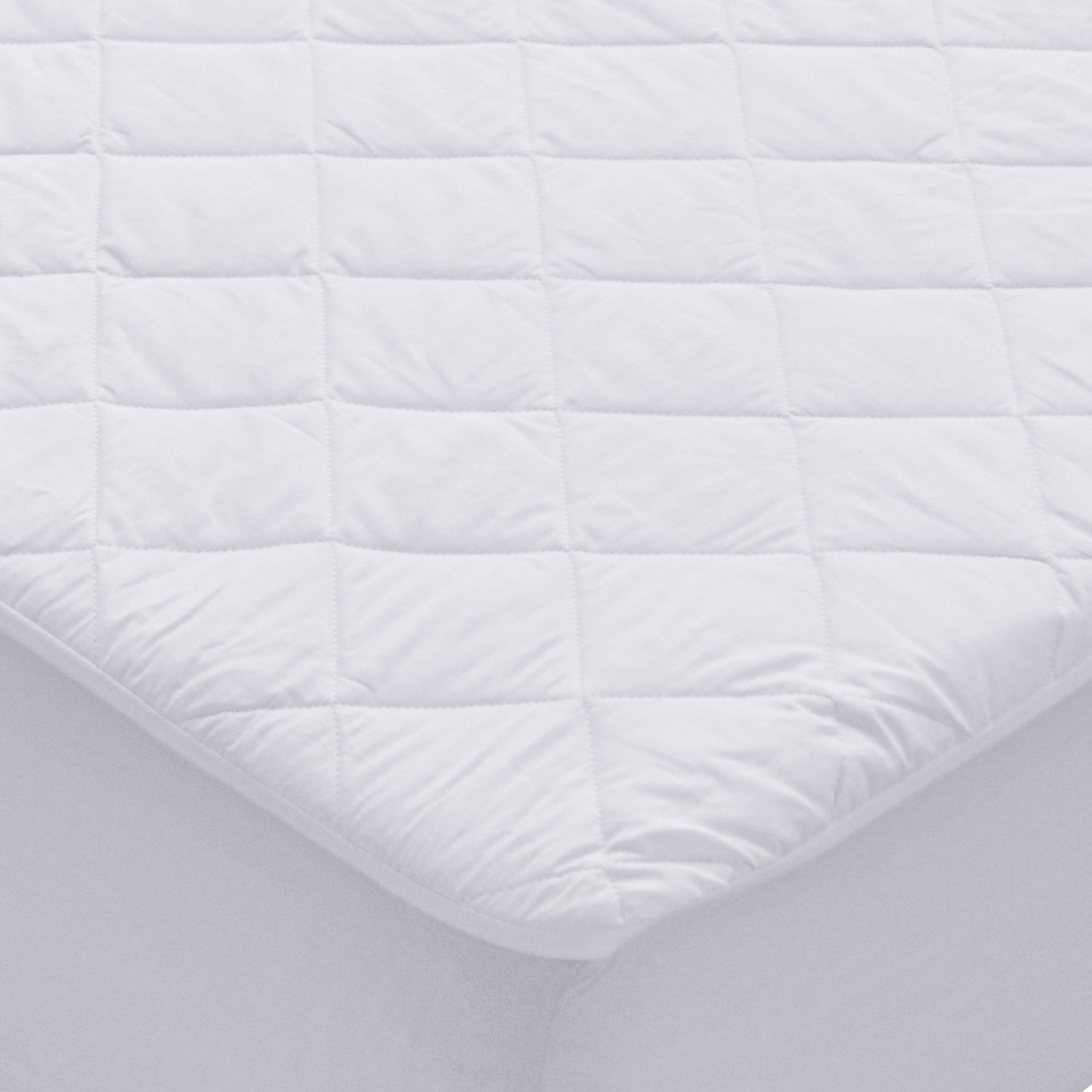 White waterproof Repreve mattress protector with diamond quilting and fitted skirt on a mattress corner.