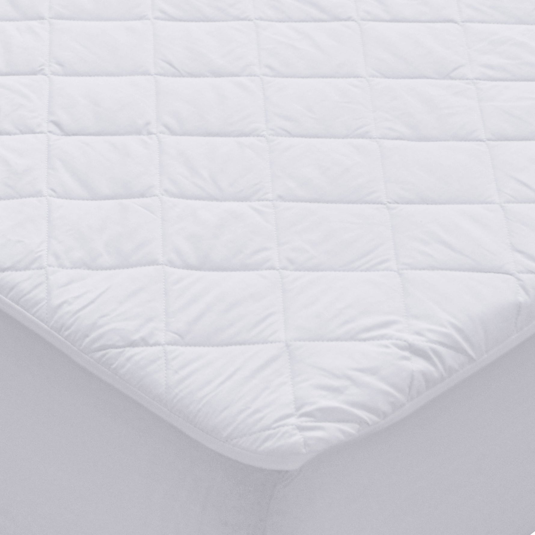 White waterproof Repreve mattress protector with diamond quilting and fitted skirt on a mattress corner.