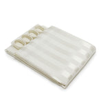 Folded off white natural shower curtain with satin stripe pattern and shower rings on a white background.