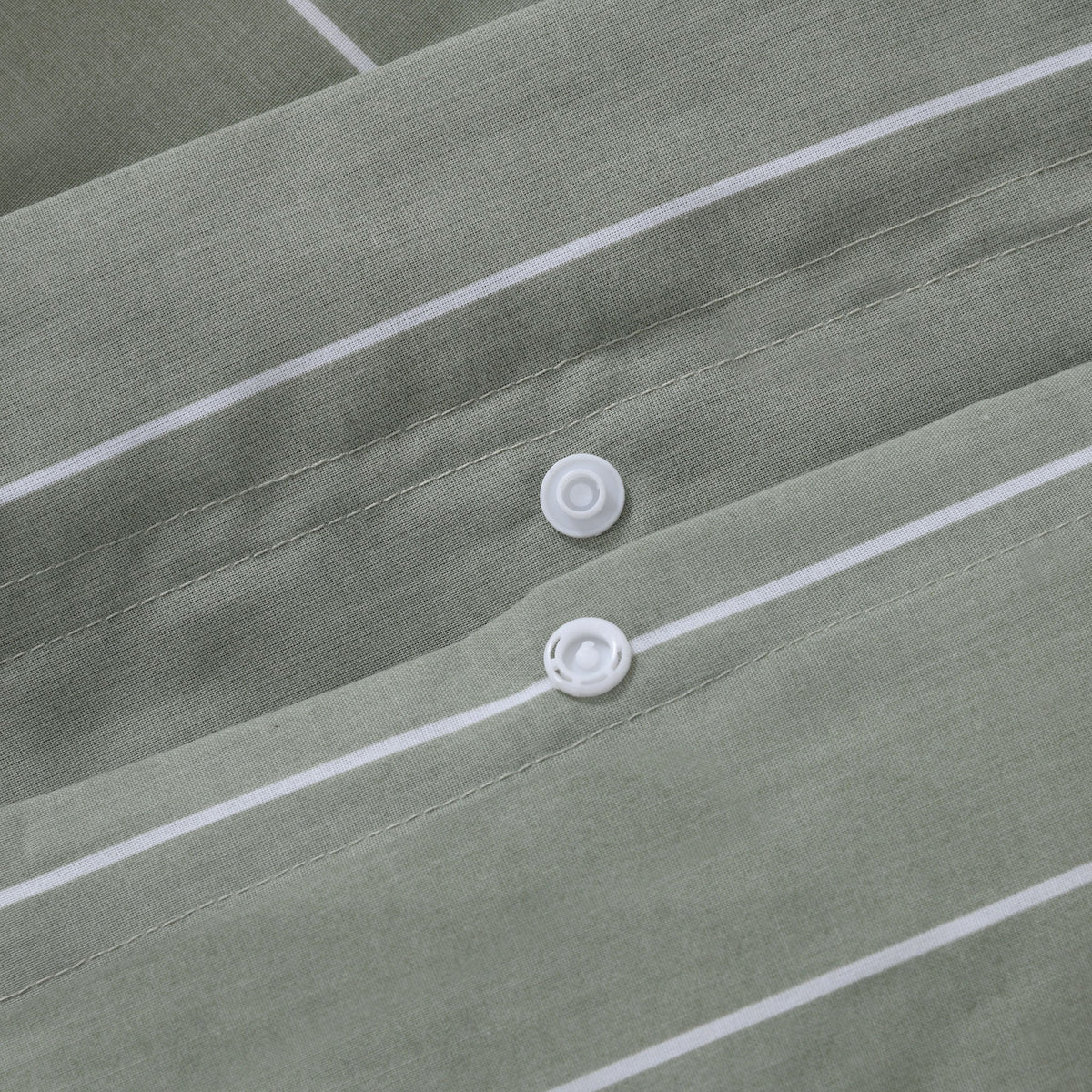Close up of snap button closure on Studio Stripe quilt cover in sage