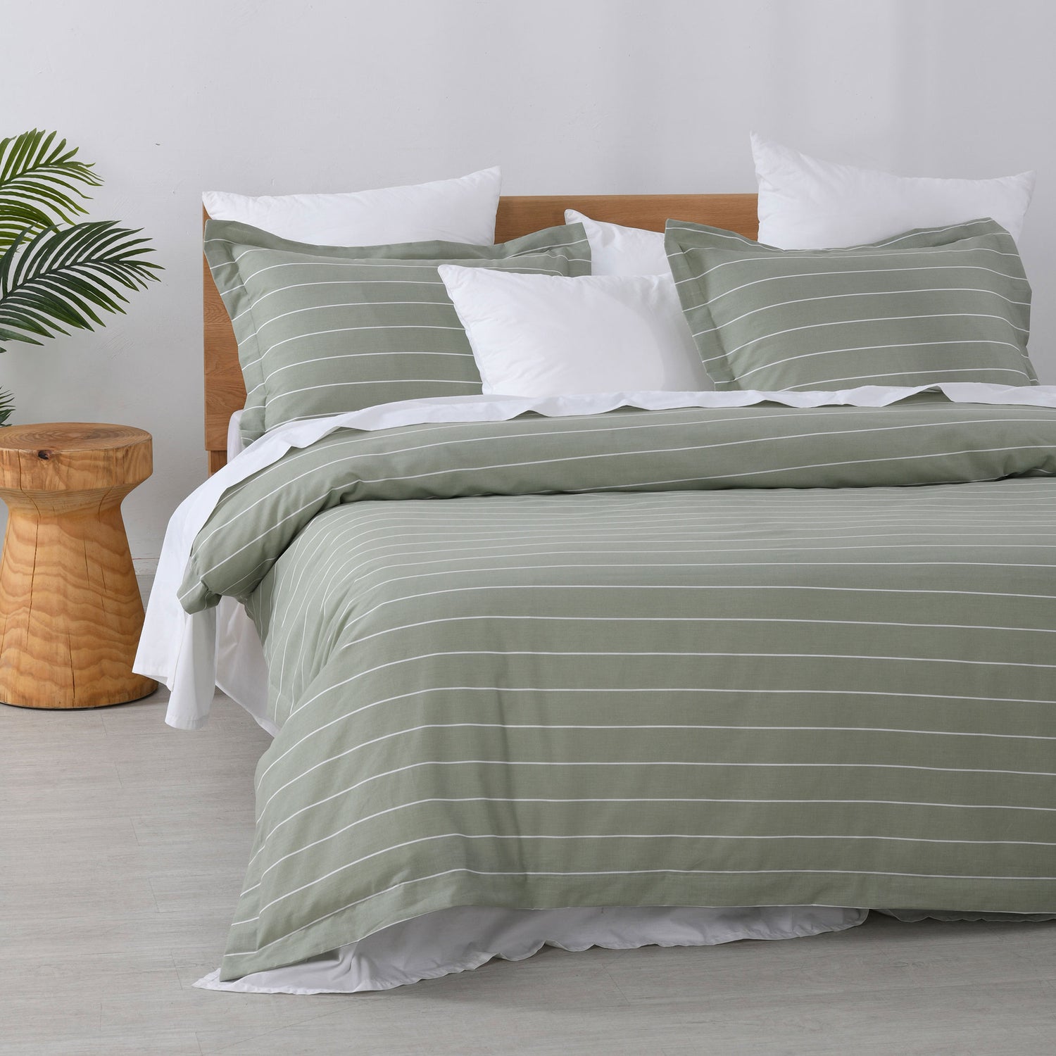 Studio Stripe quilt cover set featuring fine white pinstripes on a sage green background with matching pillowcases and white pillows on a bed.