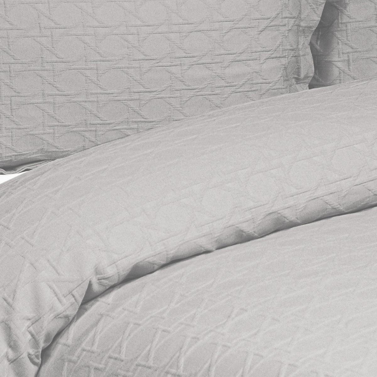 Close-up of a silver grey Villa Matelassé coverlet featuring a woven basketweave pattern, with a matching pillow sham in the background.