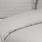 Close-up of a silver grey Villa Matelassé coverlet featuring a woven basketweave pattern, with a matching pillow sham in the background.