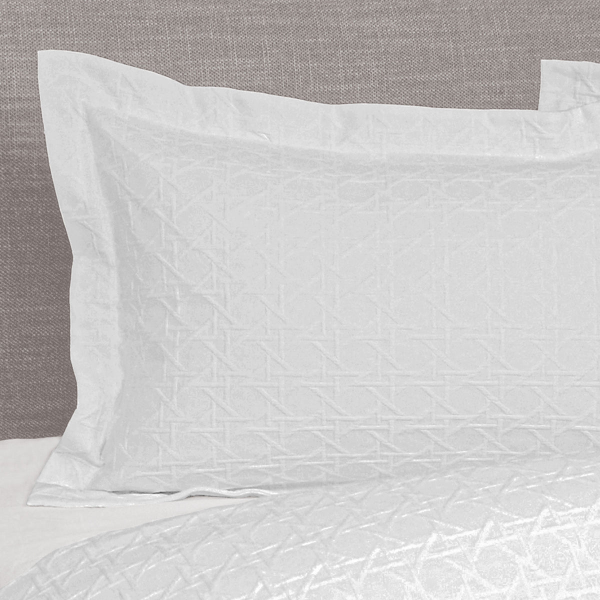 White Villa Matelassé pillow sham featuring a textured woven basketweave pattern and flanged edge, fitted over a pillow on a bed.